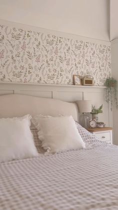 a bed with white sheets and pillows in a bedroom next to a wallpapered headboard