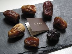 an assortment of dried dates on a slate board with a business card in the middle