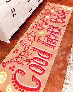 a kitchen area with a wooden floor and large rugs on the floor, along with white cabinets