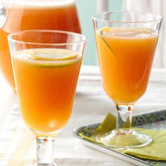 three glasses filled with orange juice on top of a table