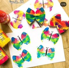 colorful paper butterflies are on the table next to paint