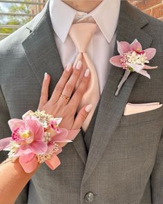 a close up of a person wearing a suit and tie with flowers on his lapel