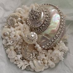 a brooch with pearls and crystals on it sitting on a piece of cloth covered in white fabric