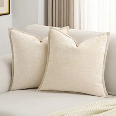 two white pillows sitting on top of a couch