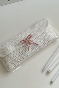 a white crocheted case with three pens on it