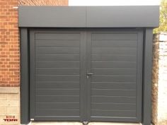 a large gray garage with two double doors and brick wall in the back ground area