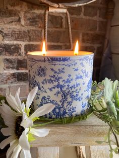 a blue and white candle sitting on top of a wooden table next to some flowers