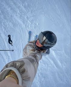 a person on skis in the snow holding their hand out to take a photo