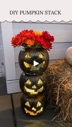 three pumpkins stacked on top of each other with flowers in them