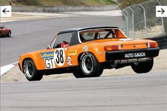 an orange sports car driving down a race track