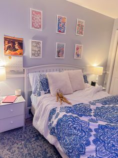 a blue and white bedroom with pictures on the wall above the bed, along with a teddy bear