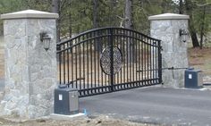 an iron gate with decorative designs on the top and bottom, surrounded by stone pillars