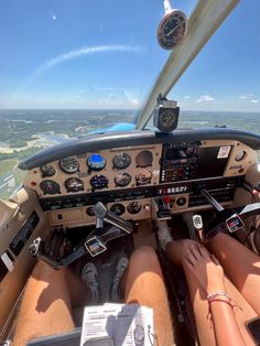 two people sitting in the cockpit of an airplane with their feet up on the ground