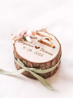 a wooden slice with wedding rings on it and a green ribbon tied around the edge