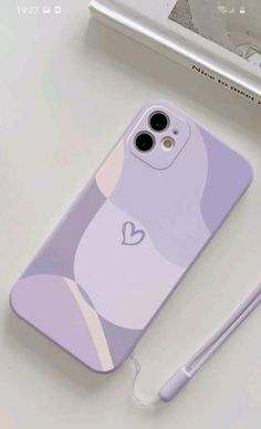 an iphone case with a heart on it next to a pen and phone charger