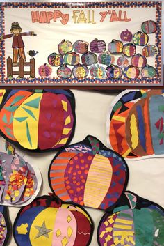 colorful paper plates are arranged in front of a happy fall wall sign and bulletin board