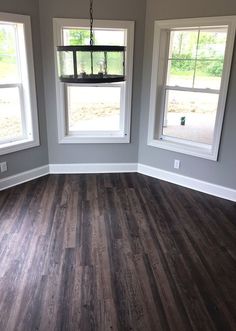 an empty room with three windows and wood flooring