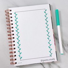 an open notebook with green leaves on it next to a pen and paper clipping