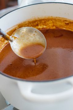 a spoon full of sauce being stirred in a pot