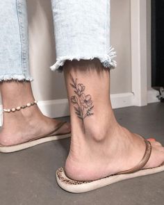 a woman's foot with a small flower tattoo on her left ankle and right leg