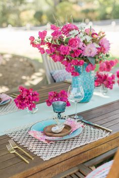 the table is set with pink flowers and plates