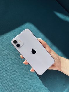 a person holding an iphone in their hand on a blue surface with sunlight coming through the window