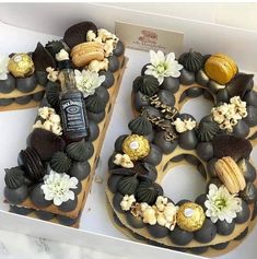 two donuts decorated with nuts and chocolates in a box