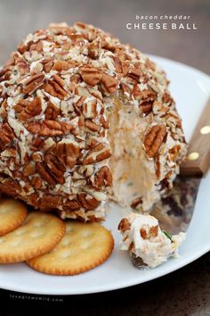 a cheese ball with pecans on top and crackers around the edges sitting on a white plate