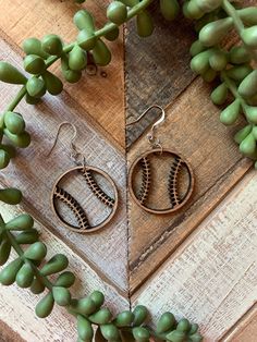 the earrings are made out of metal and have baseball stitching on them, along with green leaves