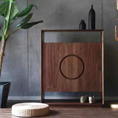 a wooden cabinet sitting on top of a hard wood floor next to a potted plant