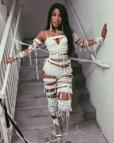 a woman in a white outfit is standing on the stairs with her arms stretched out