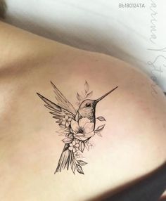 a woman's back with a hummingbird and flowers tattoo on her left side