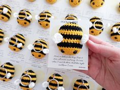 a hand holding up a tiny crocheted bee brooch on top of a card