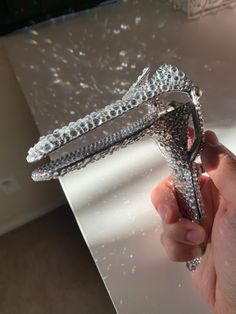 a hand holding a diamond shaped object on top of a white surface with lots of glitter