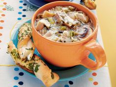 a bowl of soup on a plate next to some breads and other food items