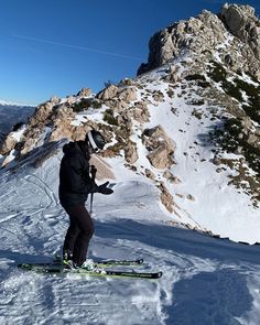 a man riding skis down the side of a snow covered slope next to a mountain