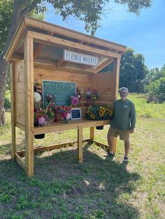 a man standing in front of a wooden booth with flowers on the table and chalkboard