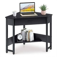 a laptop computer sitting on top of a black desk next to a clock and books