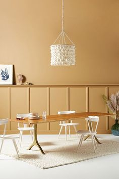 a dining room table with chairs and a chandelier hanging from the ceiling