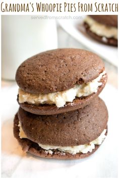 three cookies are stacked on top of each other next to a cup of milk and a glass of milk