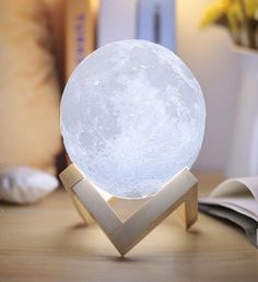 a white lamp sitting on top of a wooden table next to a book and vase