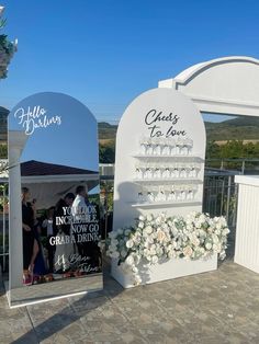 the entrance to an event with flowers and signs on it's sides that read cheers to love