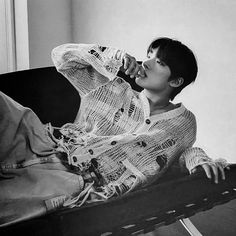 black and white photograph of a woman sitting on a couch drinking from a bottle in her hand