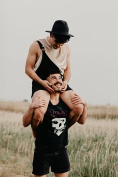 a man carrying another man on his back in the middle of an open field with tall grass