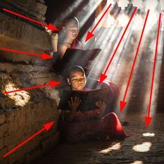 a woman sitting on the ground reading a book with red arrows pointing up at her