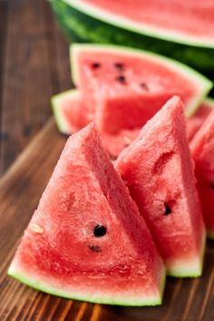 slices of watermelon sitting on top of a wooden table next to each other