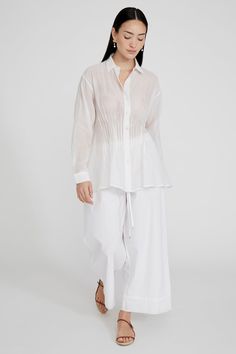 A cotton and silk blend button down blouse with pintucked detail at the waist. 70% Cotton, 30% Silk Chanderi. 24.5" Bust, 23.25" Sleeve, 38" Bottom Width, 29" Total Length. One size: Fits sizes S-L. Dry clean only. Made in India. Pleated Button-up Blouse For Daywear, Daywear Button-up Blouse With Pintucks, Button-up Blouse With Pintucks For Daywear, Button-up Daywear Blouse With Pintucks, Pintuck Button-up Blouse For Work, Cotton Blouse With Pintucks For Work, Blouse White, Button Down Blouse, Button Downs