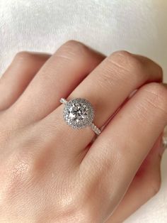 a woman's hand with a diamond ring on top of her finger and an engagement band