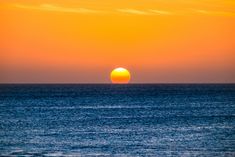 the sun is setting over the ocean on a clear day