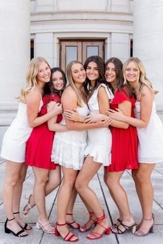 a group of young women standing next to each other in front of a white building